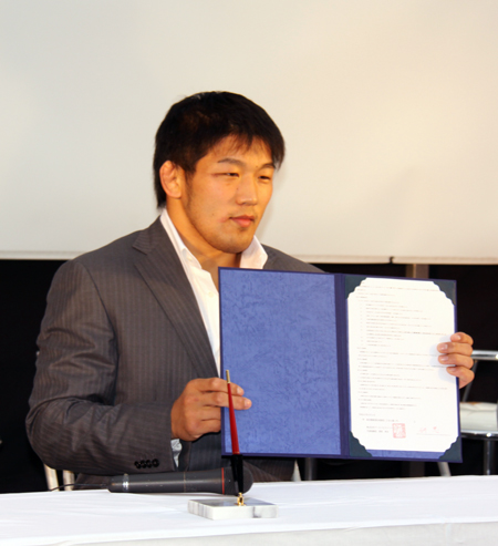 契約書にサインを済ませた石井慧